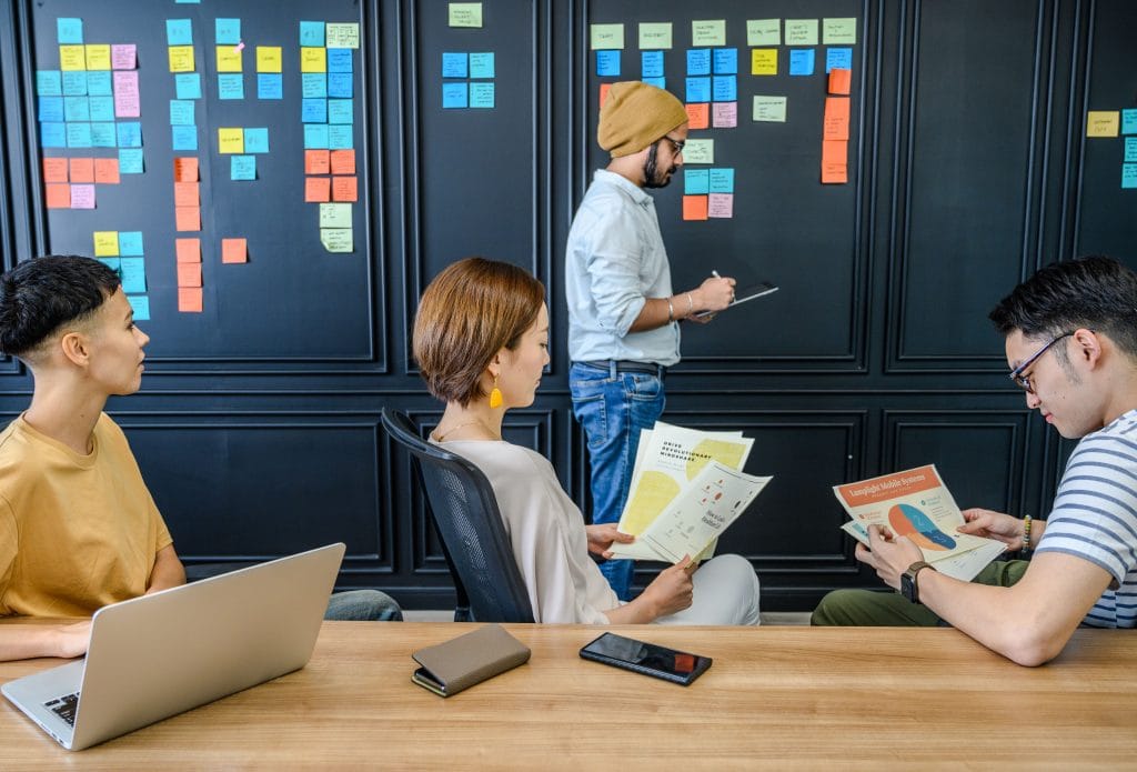 Equipe de PME planifiant la gestion de tresorerie sur des post-it colles au mur