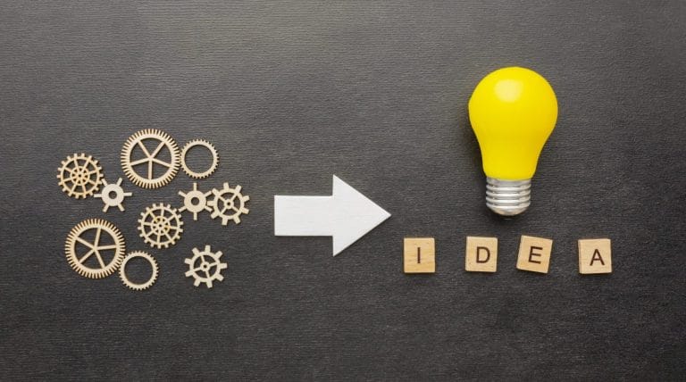Illustration conceptuelle : des rouages industriels reliés par une flèche à une ampoule allumée portant l'inscription "Idea", symbolisant comment les systèmes favorisent la créativité en entreprise selon ActionCOACH.
