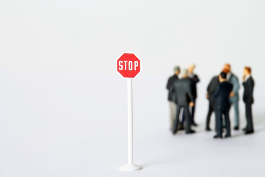 Panneau de signalisation STOP au premier plan devant un groupe de dirigeants en réflexion
